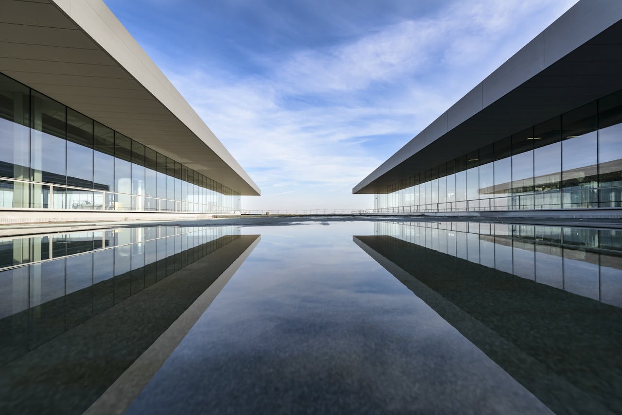 Crafting Captivating Headlines: Your awesome post title goes here Futuristic glass building mirrored on a still water surface with a cloudy sky.